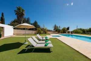 a group of lounge chairs and an umbrella next to a swimming pool at Villa Can Blai in Santa Eularia des Riu