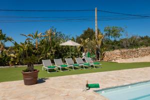 a group of chairs and an umbrella next to a pool at Villa Can Blai in Santa Eularia des Riu