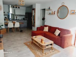 a living room with a red couch and a table at Appartement T2 Capbreton - Jardinet - Terrasse - Parking couvert in Capbreton