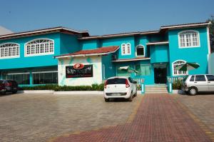 a blue building with cars parked in a parking lot at Santorini Hotel in Santarém