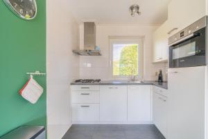 a white kitchen with white cabinets and a window at Hoogelandt 90A in De Koog +4 photos