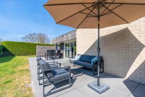 a patio with chairs and an umbrella at Hoogelandt 90A in De Koog