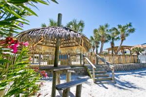 a bench and umbrella on the beach with palm trees at Surf & Sand Hotel in Pensacola Beach