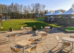 a patio with tables and chairs and a playground at Fairwood Lakes Holiday Park in Westbury