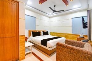 a bedroom with a bed and a tv and a couch at Super Hotel O Maa Bhubaneswari Hotel in Bhubaneshwar