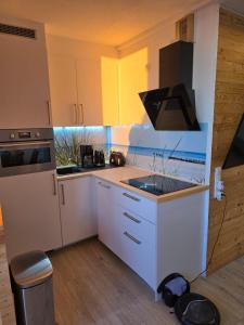 a kitchen with white cabinets and a stove top oven at Moderne Wohnung mit Sonnenuntergang über dem Meer in Heiligenhafen +2 photos