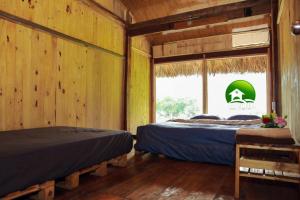 two beds in a room with wooden walls and a window at Ba Be Retreat in Bak Kan
