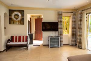 a living room with a couch and a flat screen tv at Tamasha Luxury Villa - Diani in Diani Beach