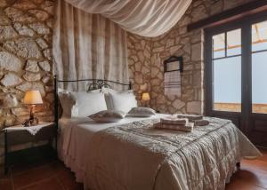 Un dormitorio con una cama y una pared de piedra. en Armos Stone Villa - Private Pool & Sea Views, by ZanteWize, en Skinária