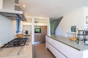 cocina con encimeras blancas y fogones en De Wadden Parel - Villa 184, en Den Burg 17 fotos más