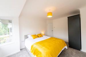 a bedroom with a bed with yellow sheets and a window at Spacious 3-Bed by Beatles Attractions & Transport in Liverpool