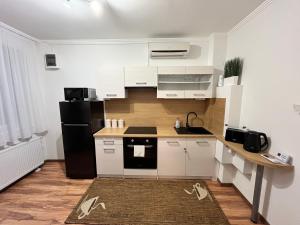 a kitchen with white cabinets and a black refrigerator at 4ML Boutique Room in Debrecen
