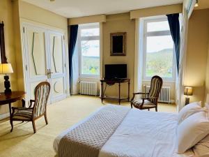 a bedroom with a bed and two chairs and a television at Domaine de charme sur lac privé in Dirac