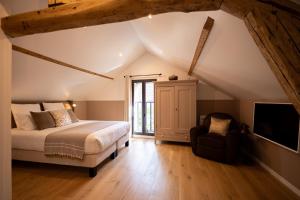 a bedroom with a bed and a tv and a chair at L'Atelier des Magnolias in Aumont