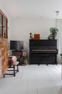 a living room with a black piano and a tv at Lovely cozy houseboat Rembrandt, old centre Leiden in Leiden