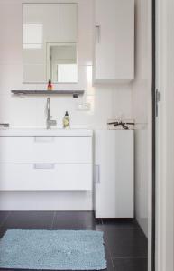 a kitchen with white cabinets and a sink and a blue rug at Lovely cozy houseboat Rembrandt, old centre Leiden in Leiden