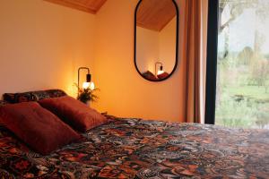 a bedroom with a bed and a mirror and a window at Ten Domek in Wola Wereszczyńska
