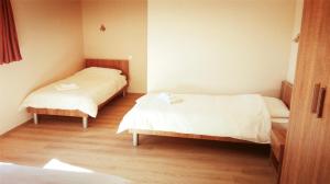 two beds in a small room with wooden floors at Pansion Eden in Međugorje