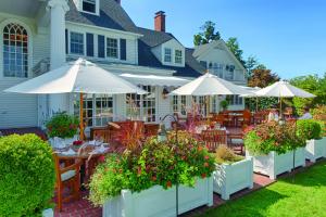 un patio con mesas y sombrillas frente a una casa en Inn at Perry Cabin en Saint Michaels