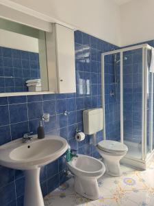 a blue tiled bathroom with a sink and a toilet at Appartamento in villa in Forio d'Ischia +12 photos