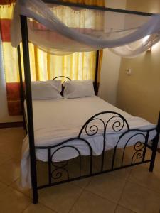 a bed with a black frame and white sheets at 2M lodge Tarangire in Manyara