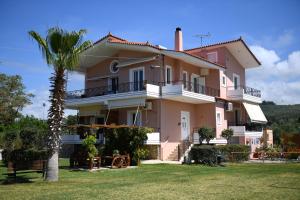 a house with a palm tree in front of it at Nonta's Garden - nature & waves in Yiannitsokhórion
