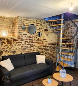 a living room with a black couch and a brick wall at Maison cosy avec jardin privé proche gare in Le Mans