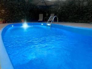 a large swimming pool with blue water at night at Zafferana's Pool Retreat in Zafferana Etnea