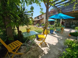 a patio with a table and chairs and an umbrella at Maison Fossemagne in Melle