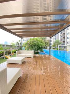 a wooden deck with white furniture and a swimming pool at Luxurious condo with City View in Cebu City +11 photos