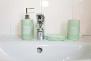 a bathroom sink with two green soap dispensers on it at 5bed house town centre location up to 10 guests in Eastbourne +43 photos