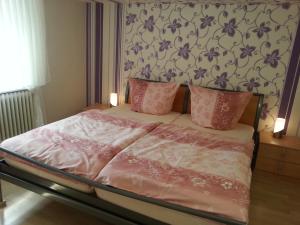 a bed with pink sheets and pink pillows in a bedroom at Ferienwohnungen Angela - Ruhe, Komfort und Erholung im Grünen in Bad Marienberg