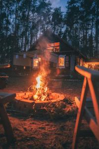 a campfire in front of a house at night at Babi Domek - Leśny dom z balią in Kruczy Borek