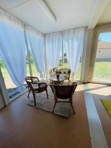 a living room with a table and chairs and large windows at GreenPark Tiny House, Garden Terrace & Parking in Bekecs