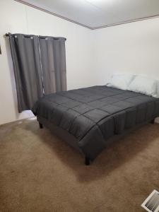 Bett in einem weißen Zimmer mit einer grauen Decke in der Unterkunft Samburg get a Way in Hornbeak