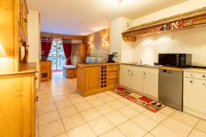 a large kitchen with white cabinets and a microwave at Alba Lodge, 2 min de la télécabine, vue montagnes in Brides-les-Bains