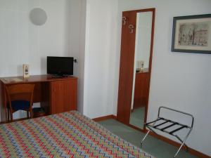 a bedroom with a bed and a desk and a mirror at Hotel Naonis in Cordenons