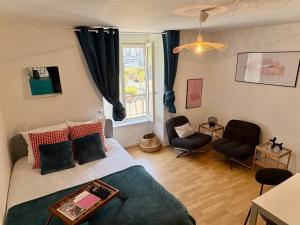 a bedroom with a bed and two chairs and a window at La Bonbonnière Centre ville - Thermes - Netflix in Mont-Dore