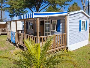 a small white house with a porch on a field at Camping La Prévoté in Saint-Hilaire-de-Riez