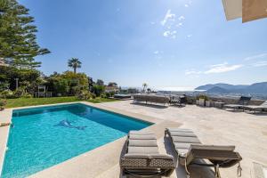 una piscina con tumbonas junto a una casa en REF 2165- Mandelieu La Napoule- Sea view Villa for rent, en Mandelieu-la-Napoule