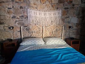 a bedroom with a blue bed with a stone wall at Su Furriadroxiu in San Vito