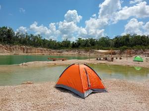 an orange tent sitting on the shore of a river at Camping Kitam in Tulum