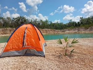 an orange tent sitting on a beach next to a river at Camping Kitam in Tulum