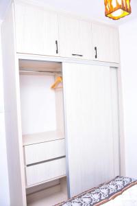 un placard avec des armoires blanches et une fenêtre dans l'établissement IMELA APARTMENT opposite ku referral, à Gatunga