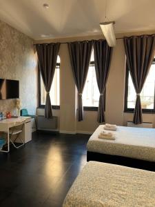 a bedroom with two beds and a desk and windows at THE ROCK HOUSE camere con bagno privato self check-in in Piacenza