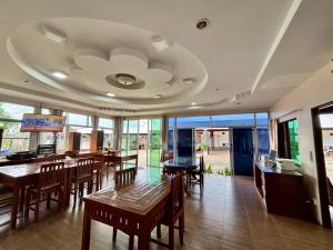 a dining room with wooden tables and chairs and windows at Garden Place in Phetchabun