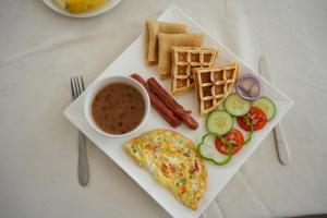 a plate of food with a omelet and sausage and vegetables at Villa Ramo in Kiwengwa