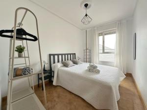 a white bedroom with a bed and a shelf at La Espina, en Somo - 30024 in Somo