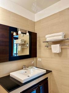 a bathroom with a sink and a mirror and towels at Ocean View Mini-Villa in Wok Tum