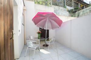 una mesa y sillas con una sombrilla rosa en el balcón en Appartement Ambre Vals les bains, en Vals-les-Bains